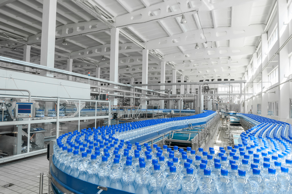 A line of capped water bottles clustered together on a conveyor belt.