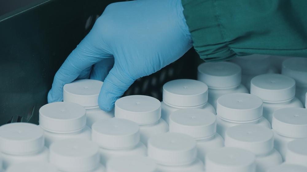 A pharmacist touching a row of pill bottles.
